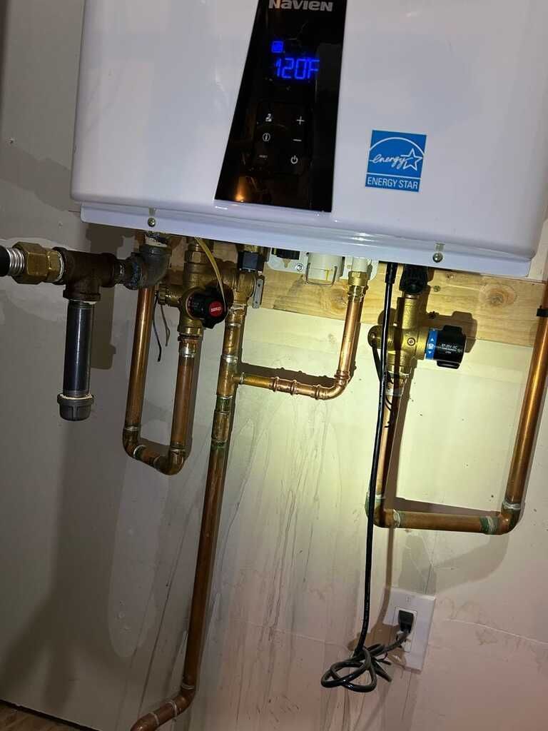Wall-mounted boiler with exposed copper pipes and valves in a utility room