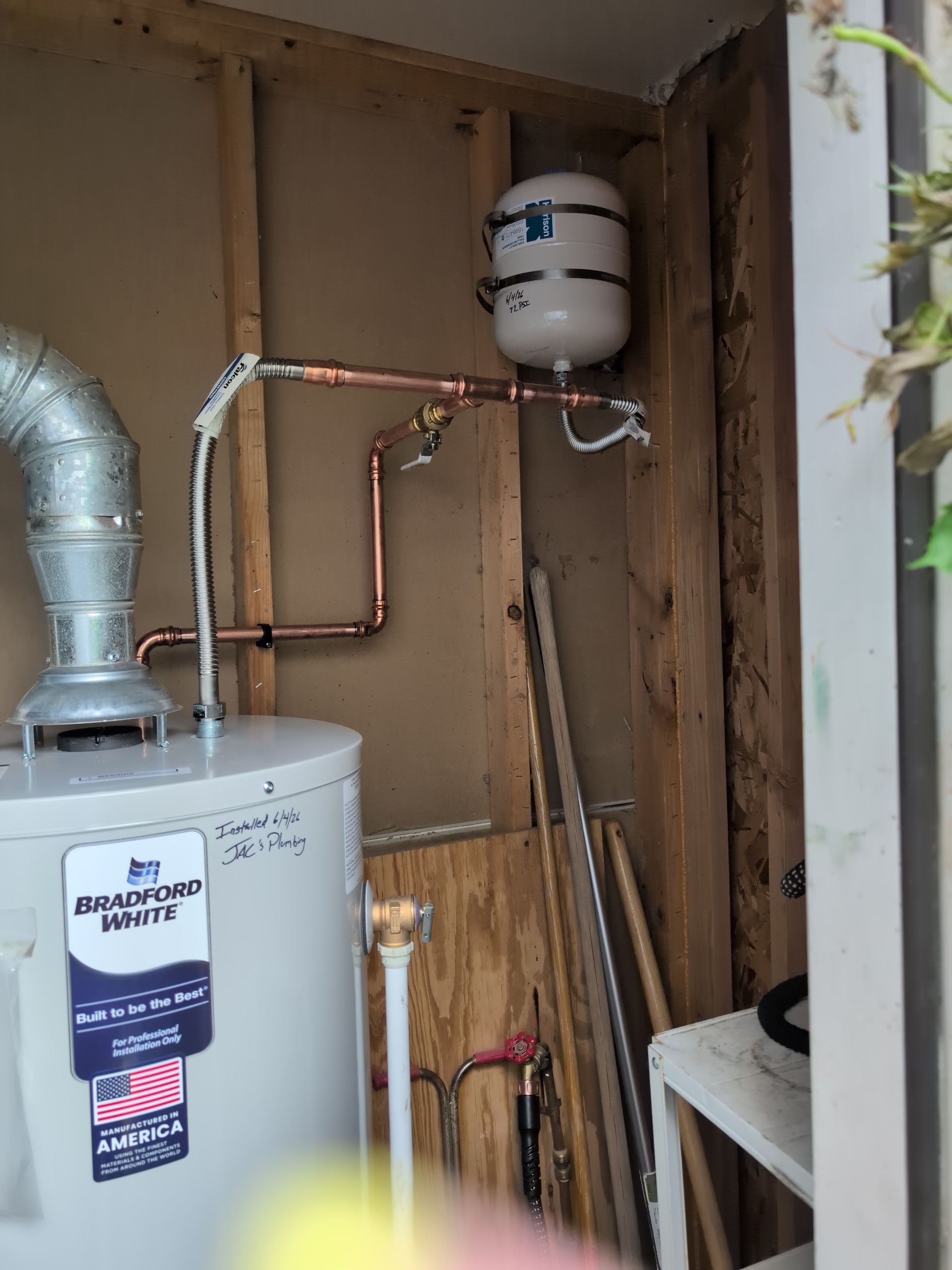 Utility closet with water heater, copper pipes, expansion tank, and exposed wall framing