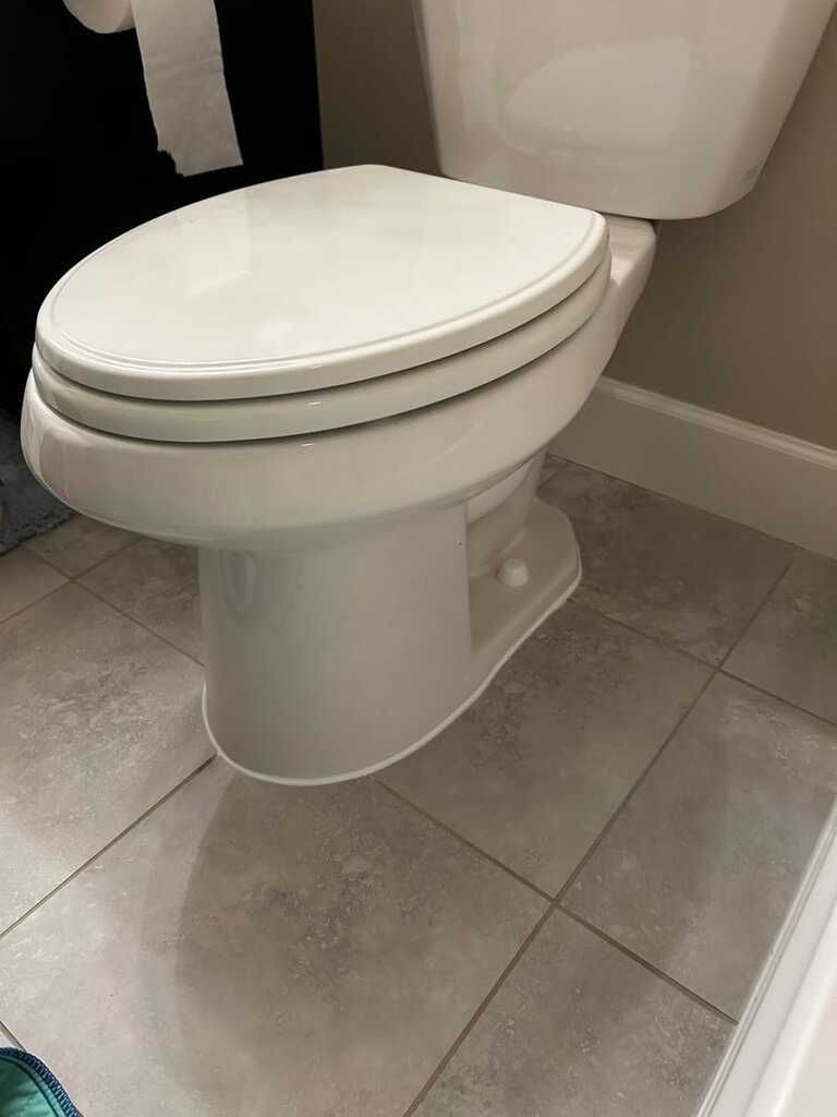 White toilet with closed lid in a tiled bathroom stall