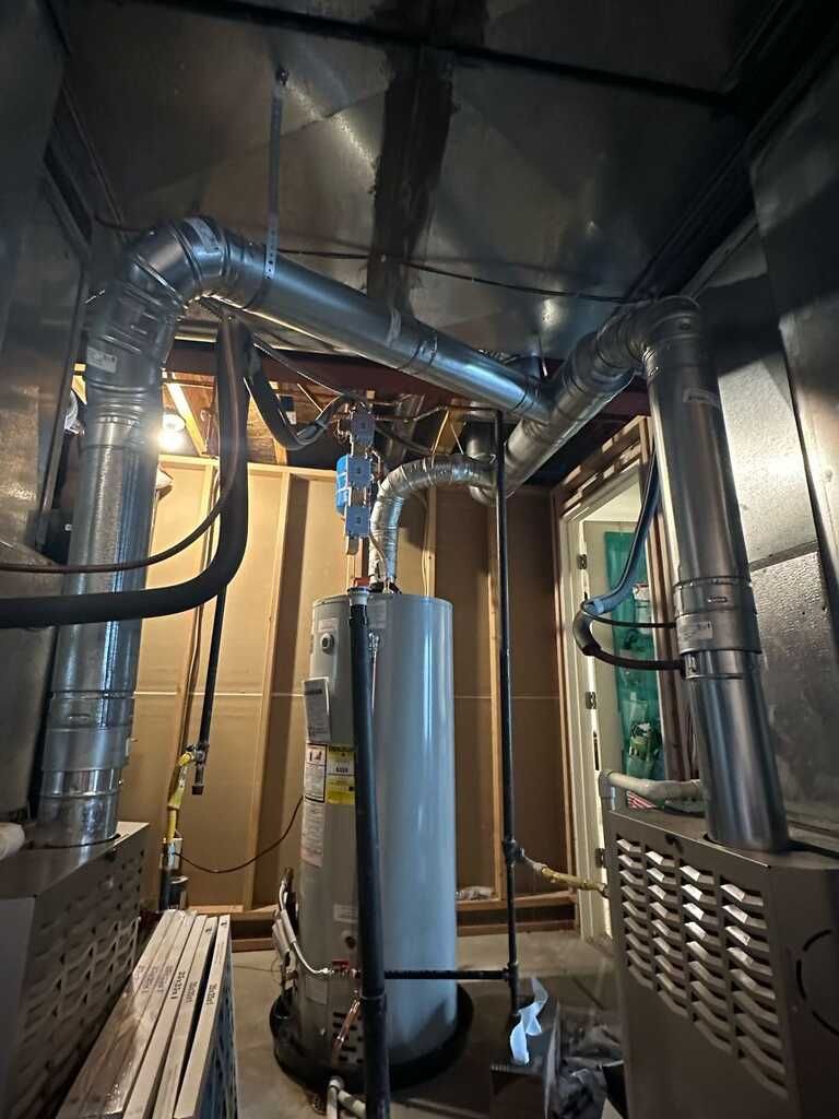 Basement utility room with water heater, metal ductwork, and pipes around a furnace system
