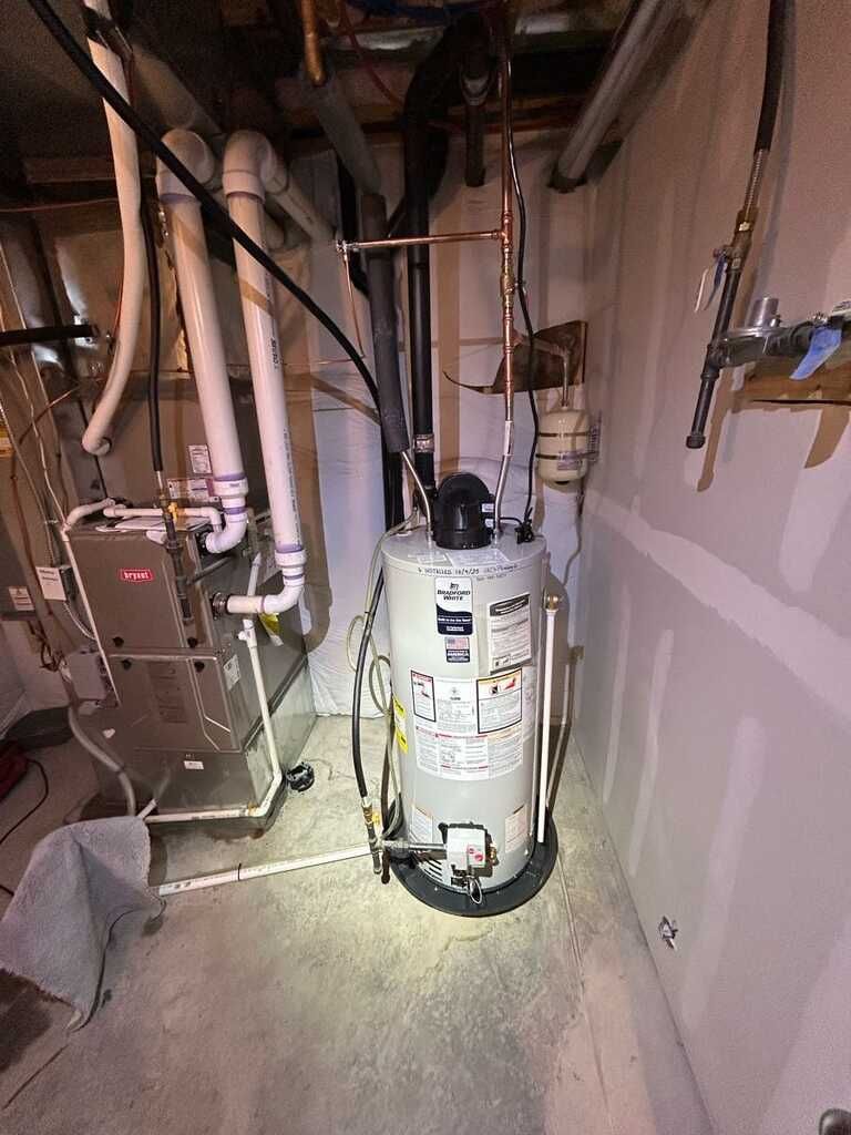 Utility closet with a water heater, exposed pipes, and a furnace in a small basement space