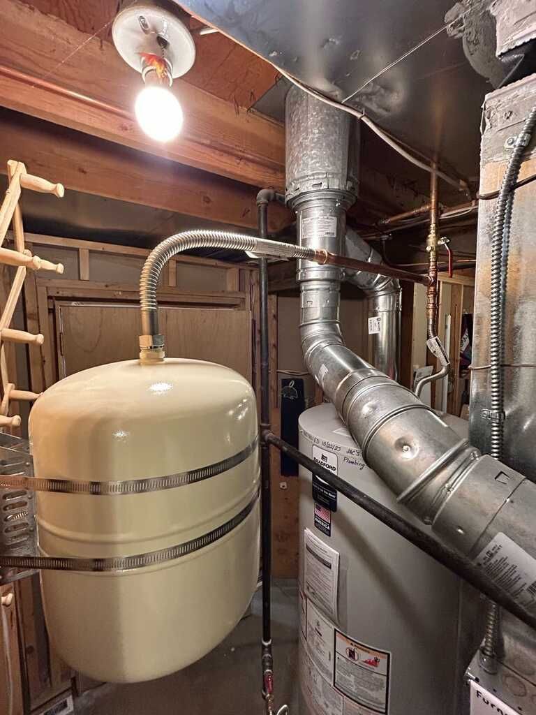 Basement utility room with furnace, ductwork, and beige expansion tank under a bare lightbulb