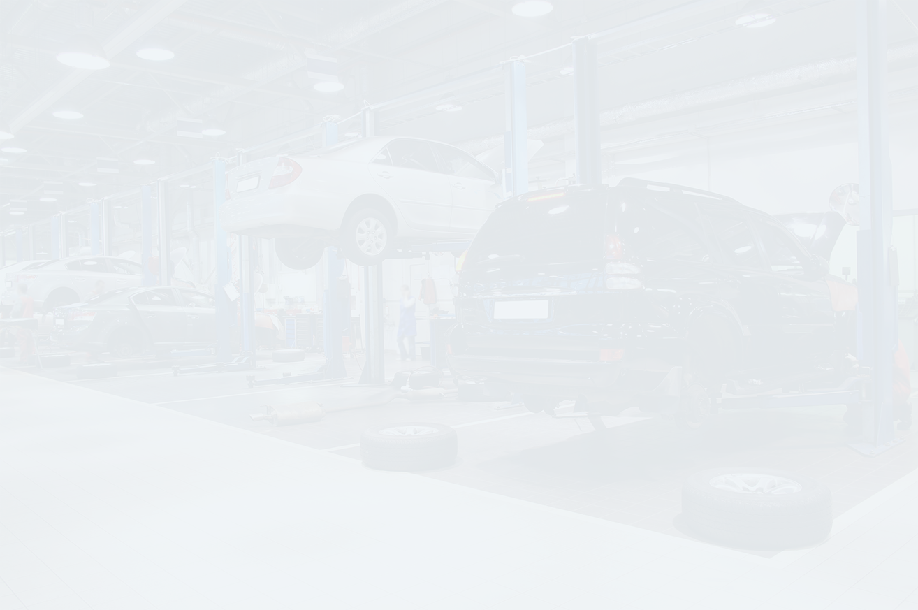 Cars on lifts in a brightly lit auto repair shop. | Joe's Auto and Tire
