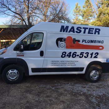 White Master Plumbing van with company logo and phone number parked outdoors