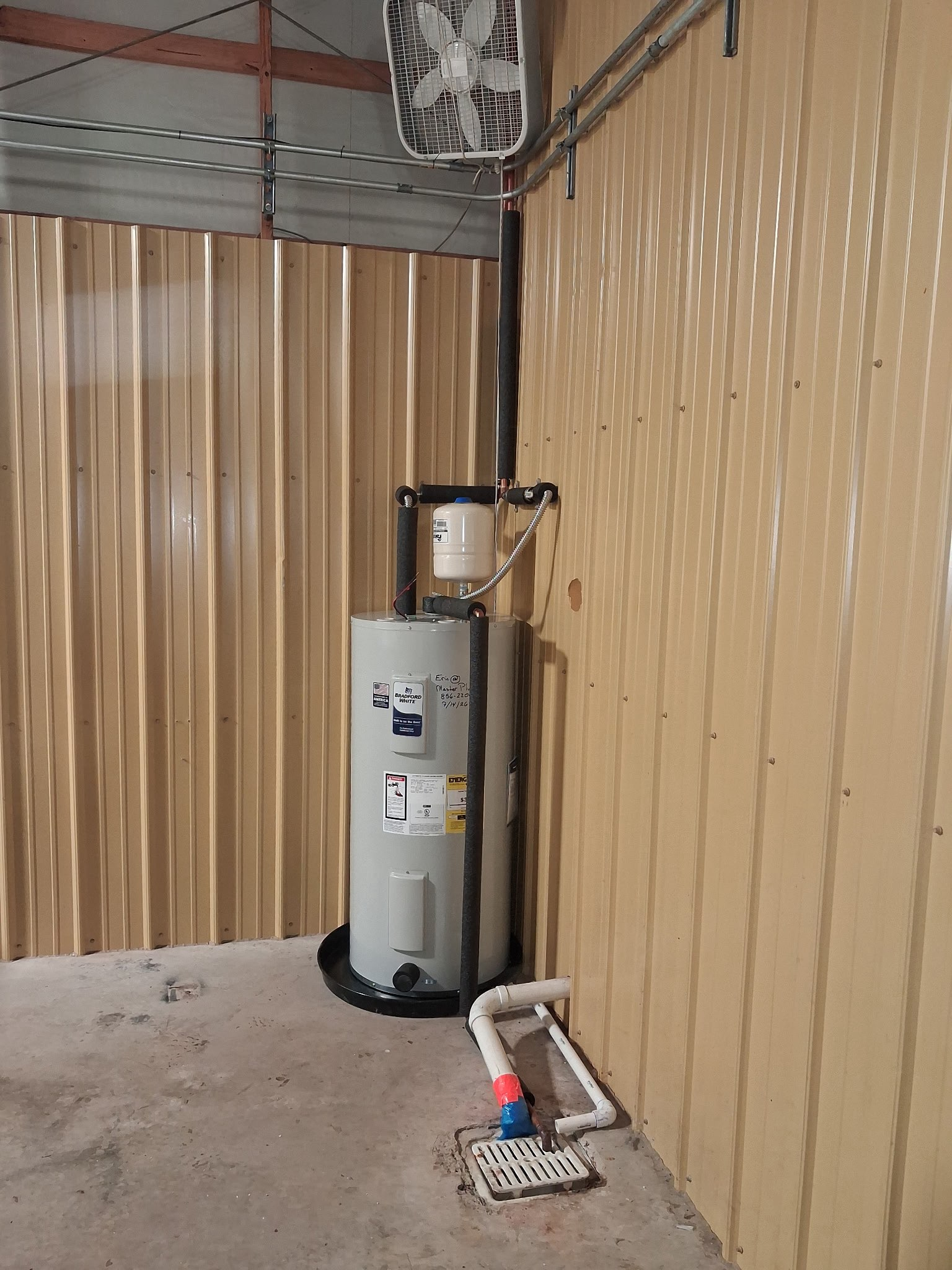 Red pump and pressure gauge on a metal pipe assembly against a concrete wall.