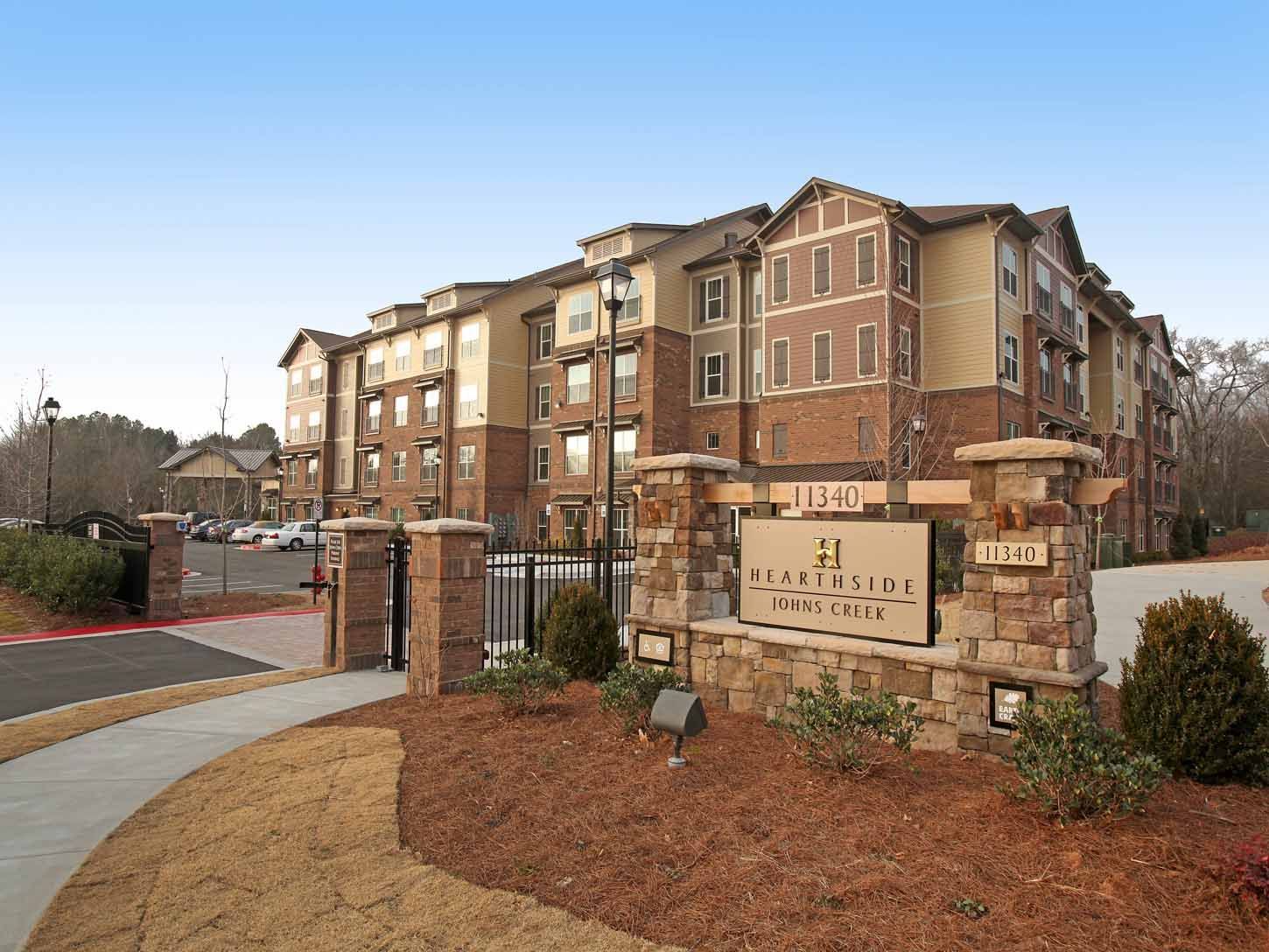 Exterior view of the apartment community entrance with a stone sign and gated entry.