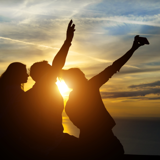 A group of people taking a selfie at sunset