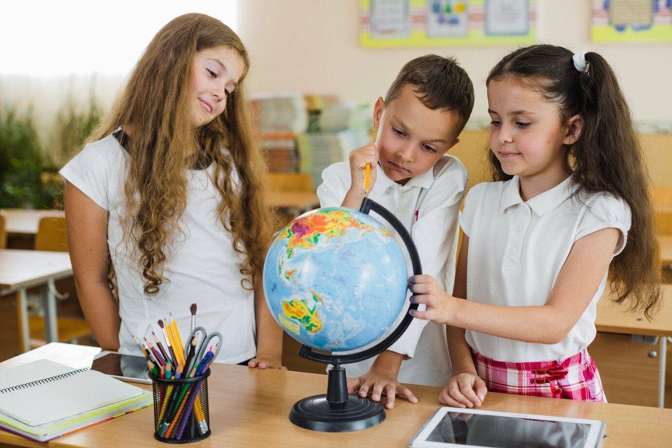 A group of children are looking at a globe in a classroom.