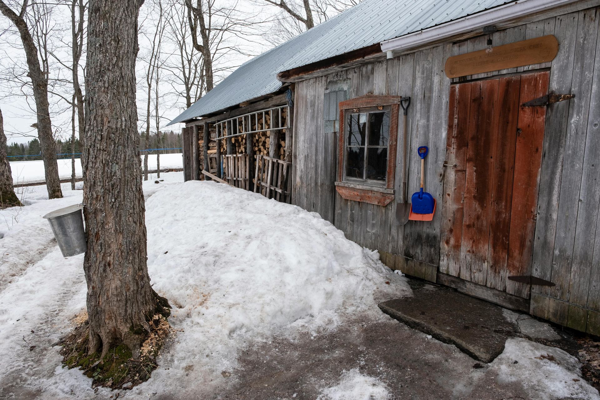 A wooden building with a snow shovel in front of it.