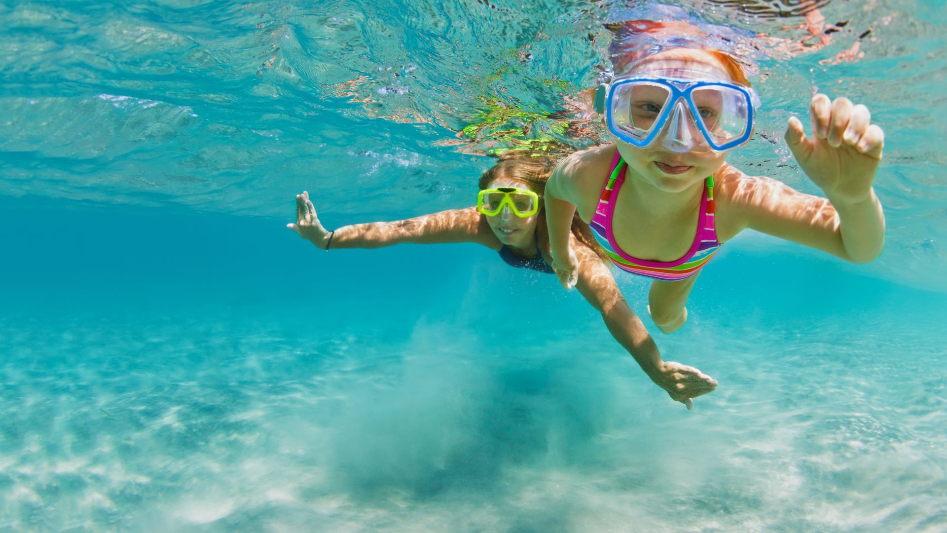 A woman and a child are swimming underwater in the ocean.