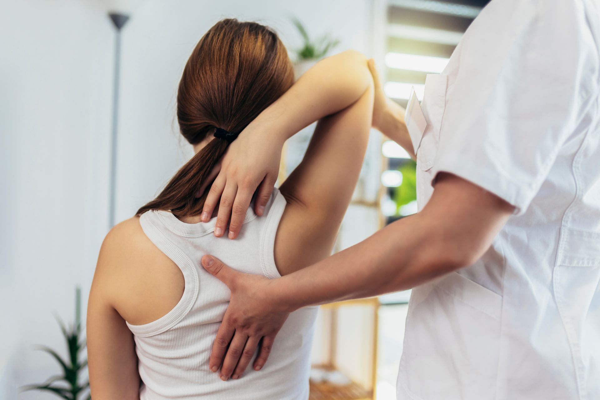 Healthcare worker examining a patient’s back with hands on the shoulder and lower back