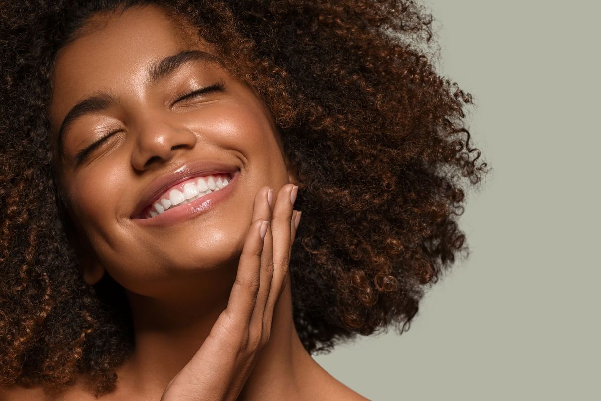 Smiling woman with glowing skin representing aesthetic services and facial rejuvenation