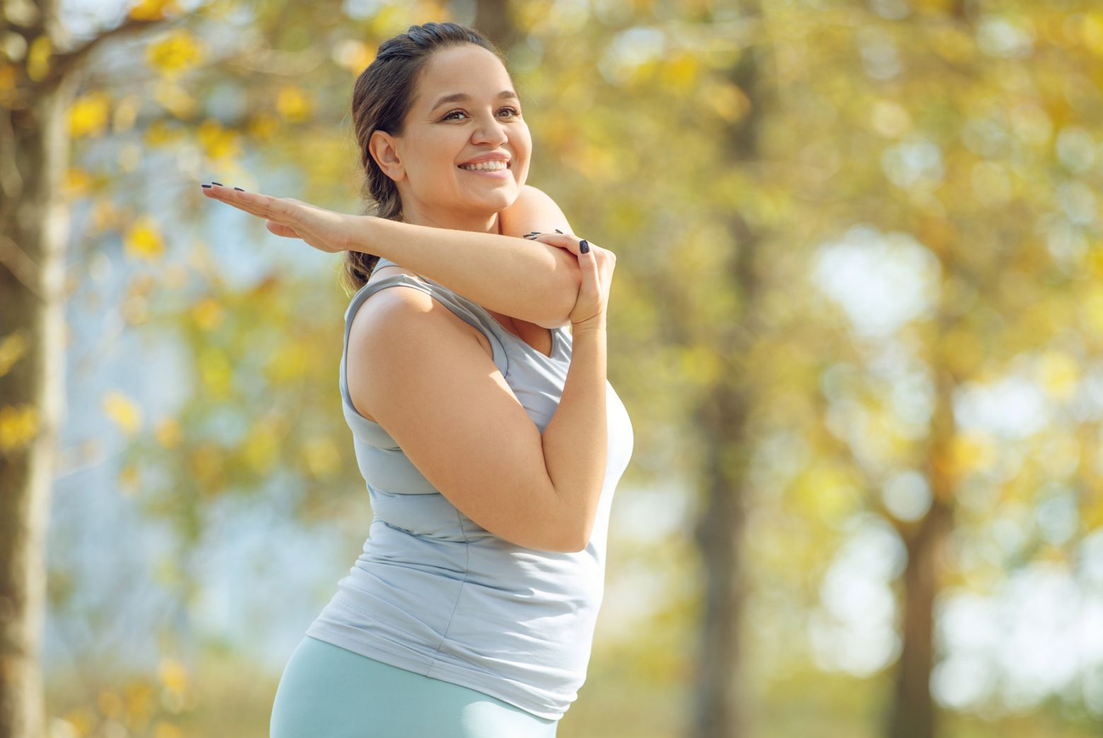 Woman stretching outdoors after non-surgical fat reduction treatment