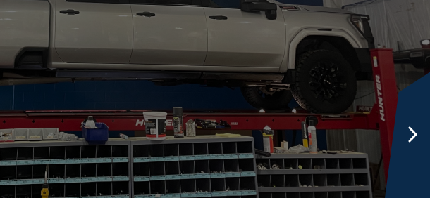 Close-up of truck tires in a garage setting with a dark blue sidebar and a right arrow | Marshside Motors