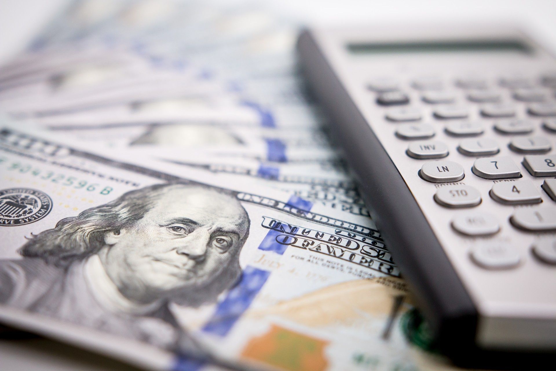 A calculator is sitting on top of a pile of money.