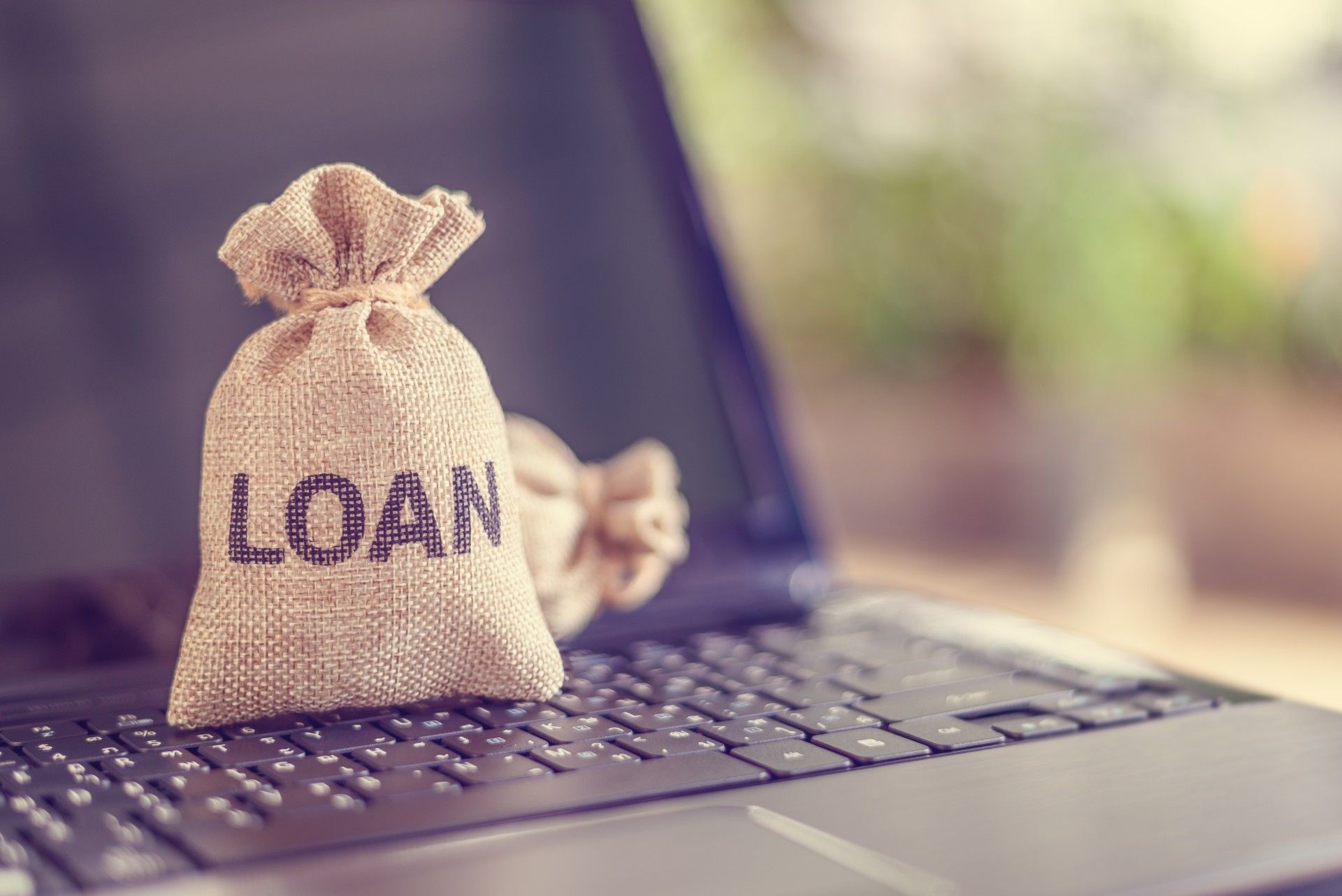 A small bag of money is sitting on top of a laptop computer.