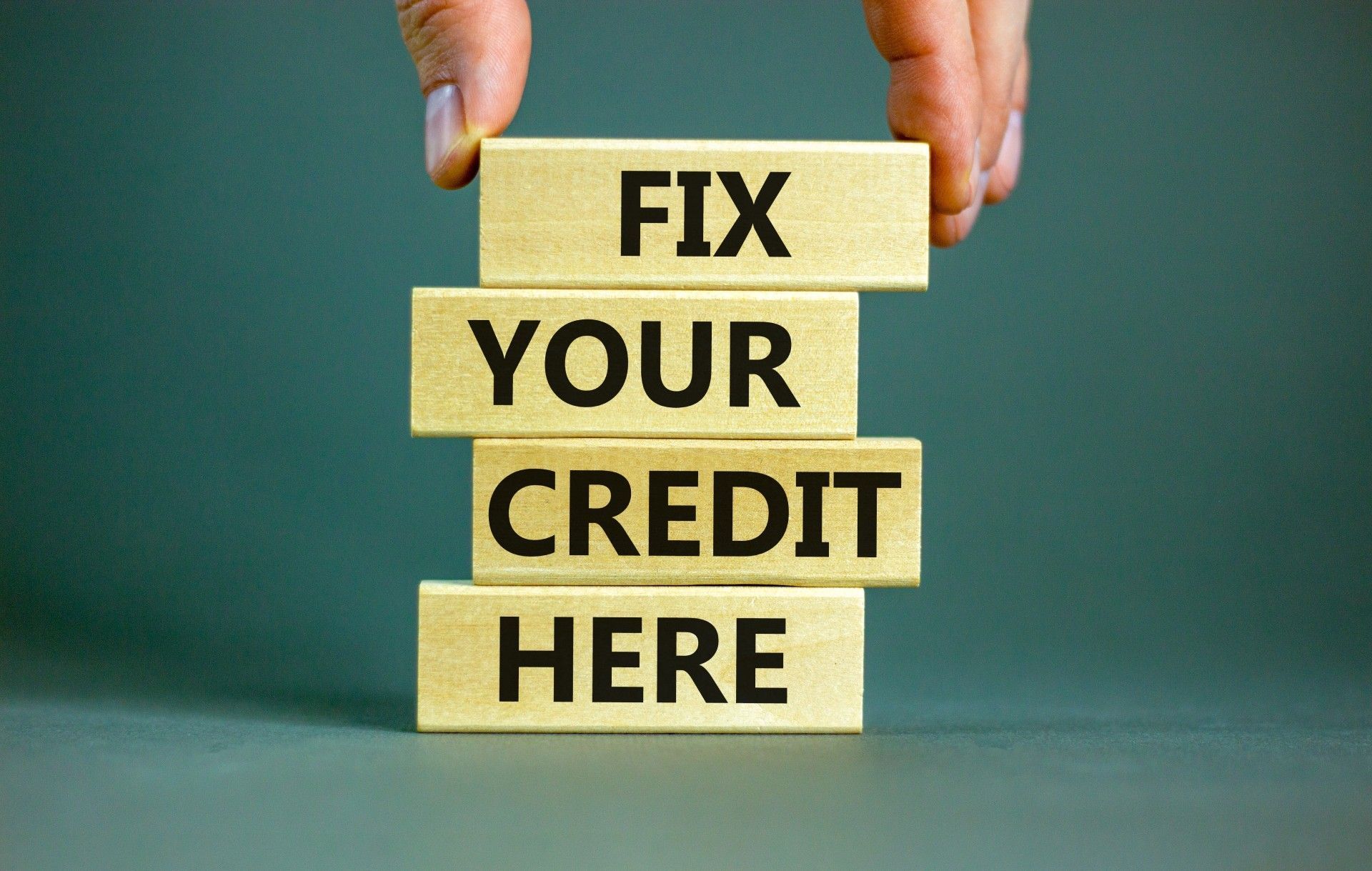 A person is holding a stack of wooden blocks that say `` fix your credit here ''.