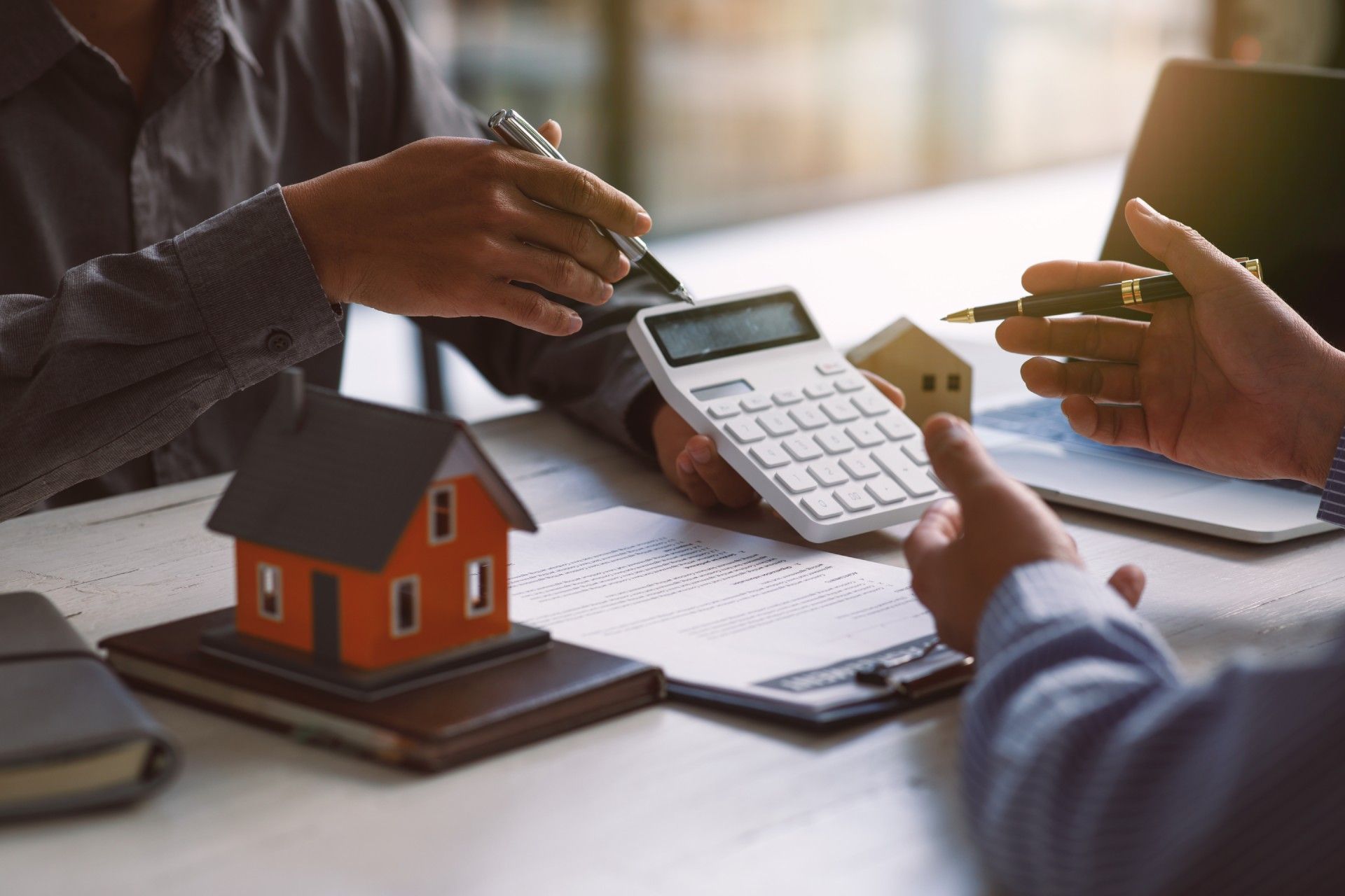 A man is using a calculator to calculate the cost of a house.