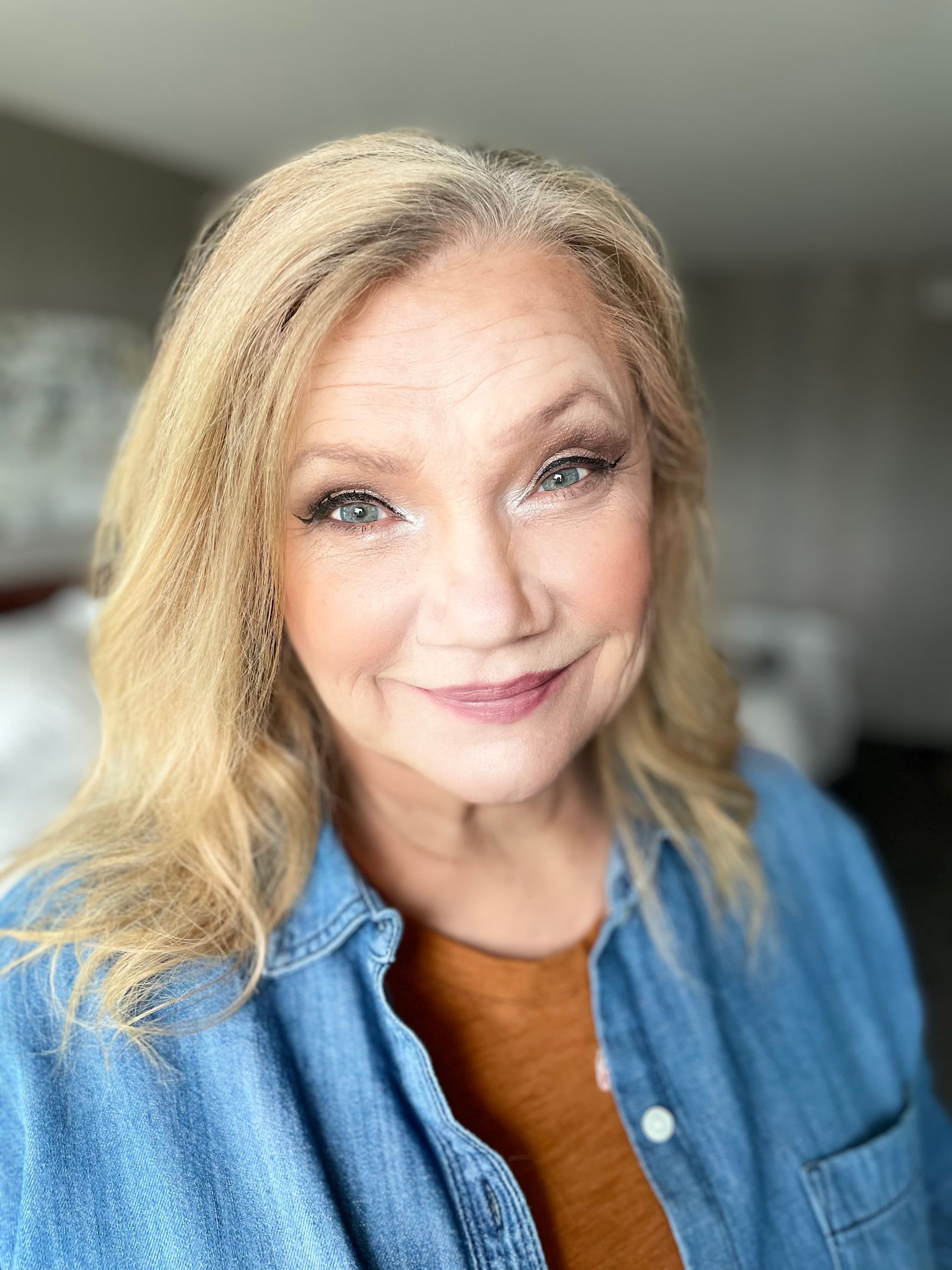 A woman in a denim shirt is smiling for the camera.