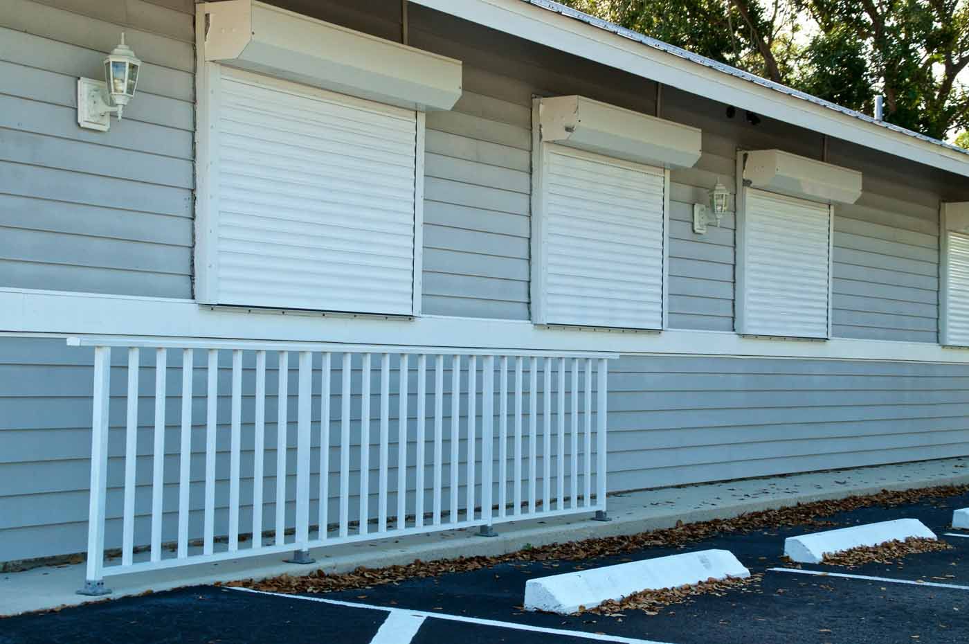 A building with white shutters on the windows and a white railing