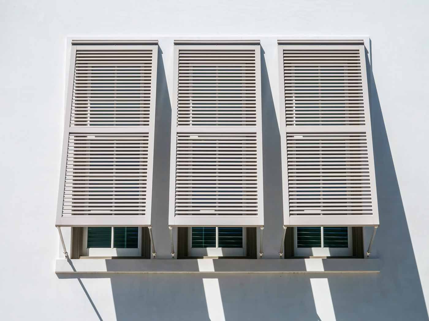 A white building with three windows and shutters on it