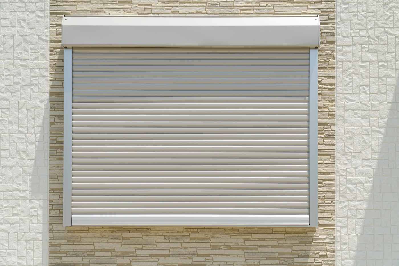 A window with a roller shutter on a brick wall.