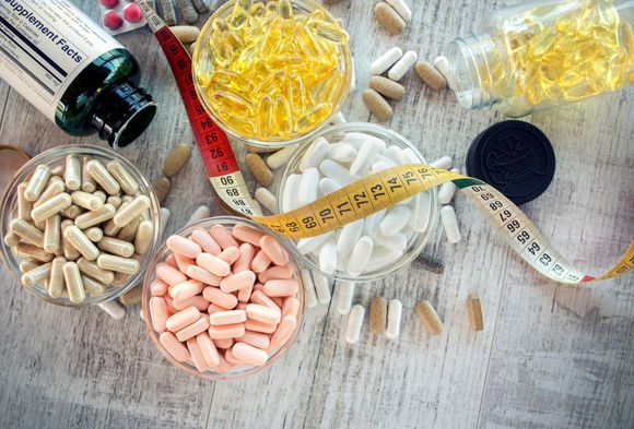 Integratori, capsule e metro a nastro disposti su una superficie ruvida, a suggerire salute o perdita di peso.