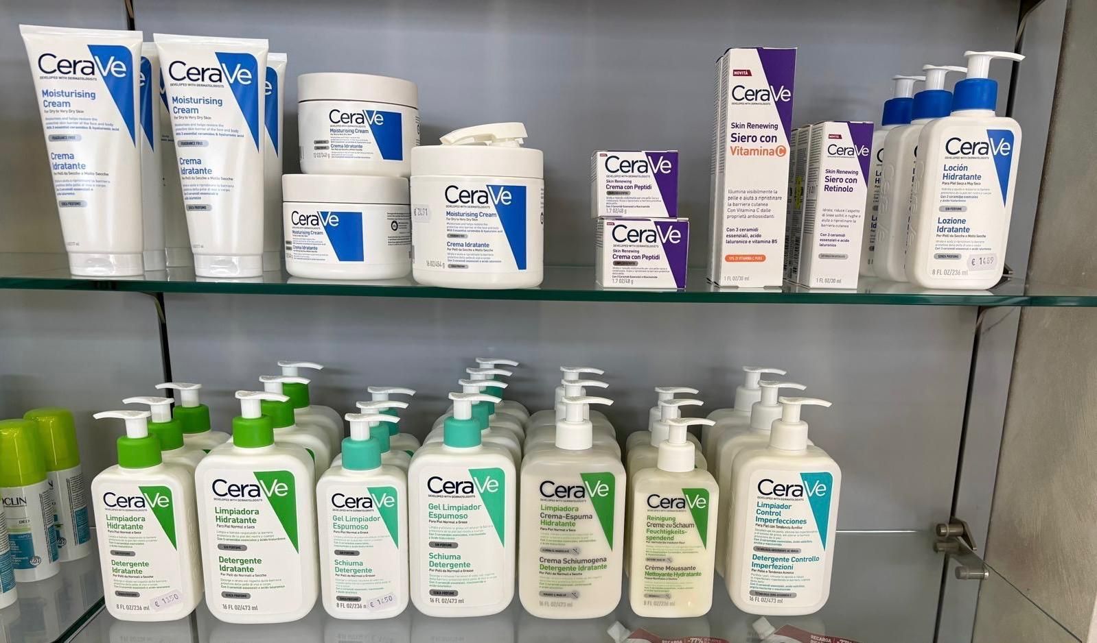 Scaffali di prodotti per la cura della pelle CeraVe in confezioni bianche, blu e verdi in una corsia di un negozio.