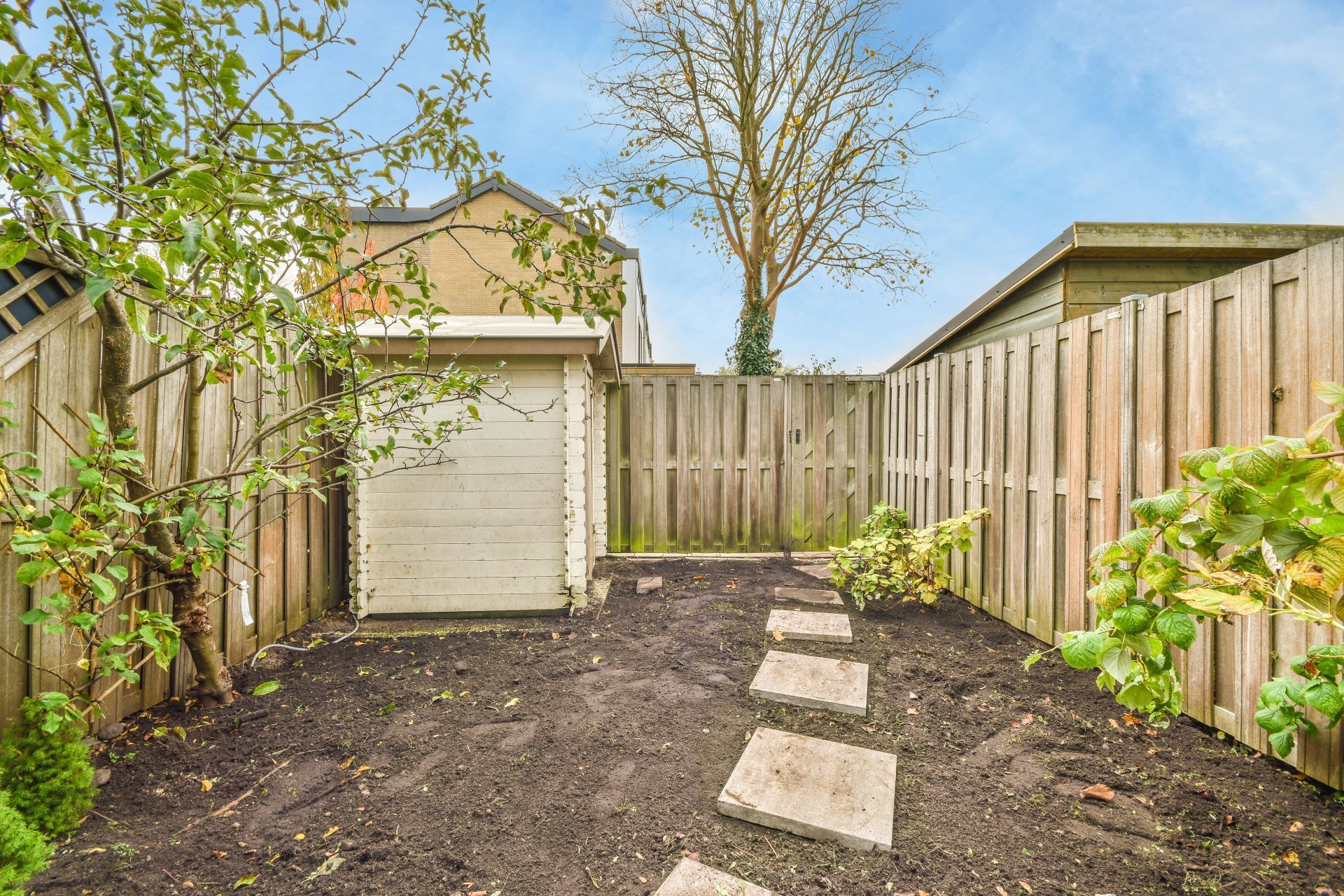 Small backyard with square stepping stones, a shed, and wooden fences.