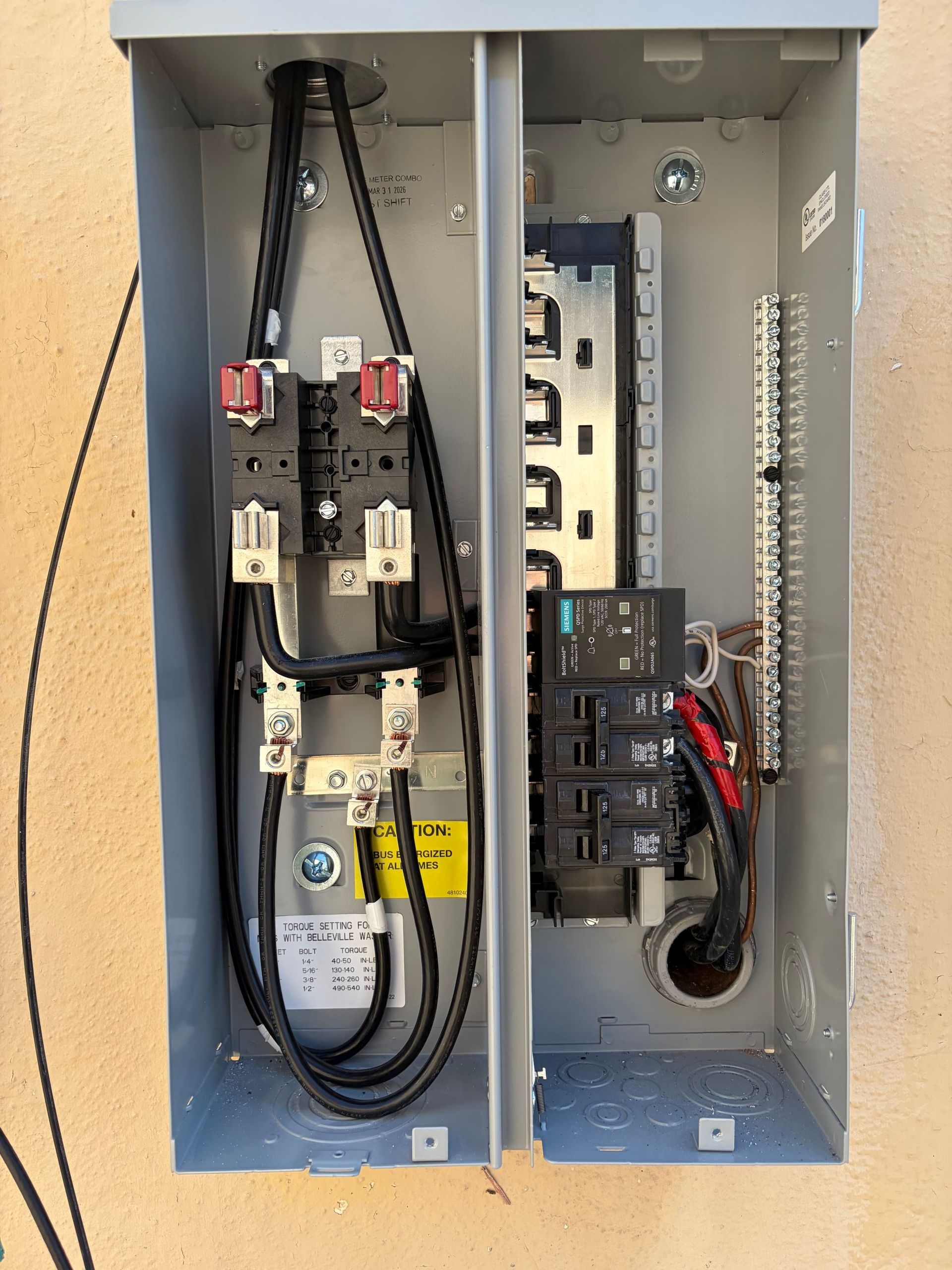 Open electrical breaker panel with wiring and circuit breakers inside a gray metal box