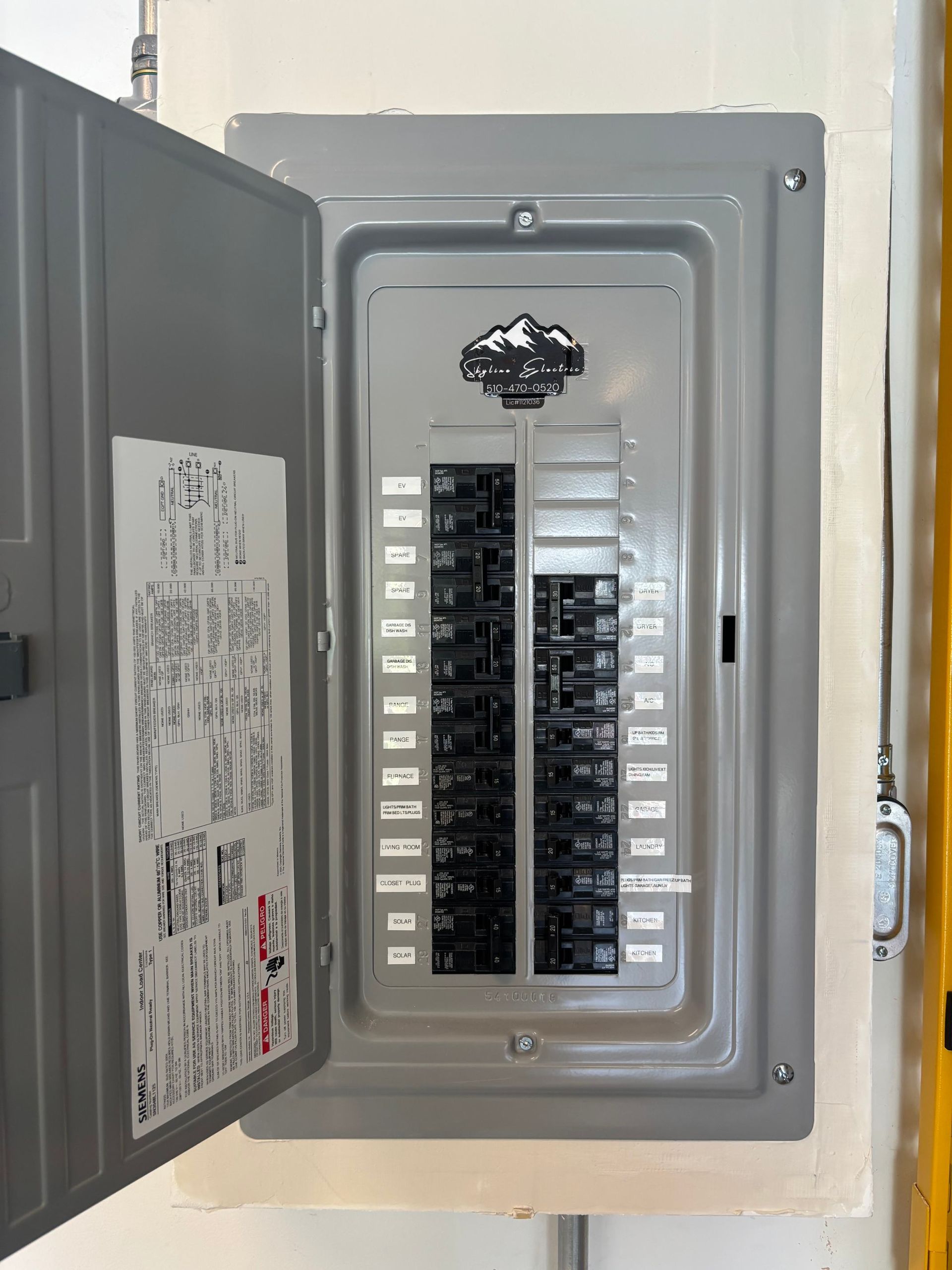 Open electrical breaker panel with multiple circuit switches and labels