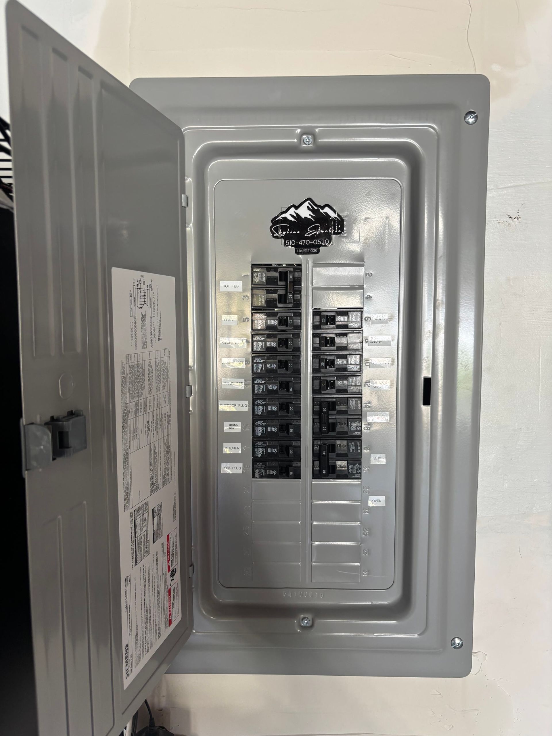 Open electrical breaker panel with door swung open and rows of switches inside