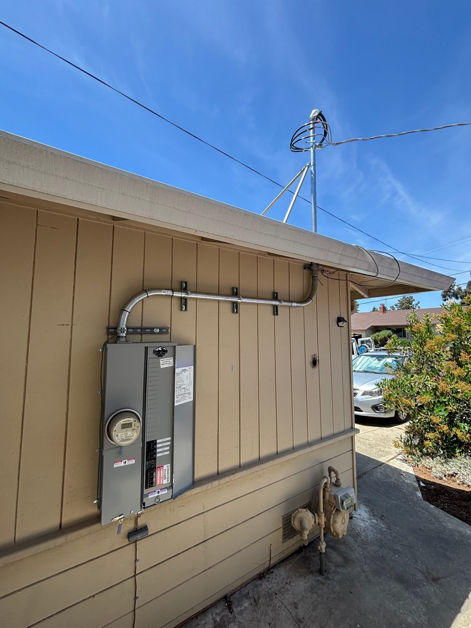 Electrical meter and utility boxes mounted on beige house wall under a blue sky
