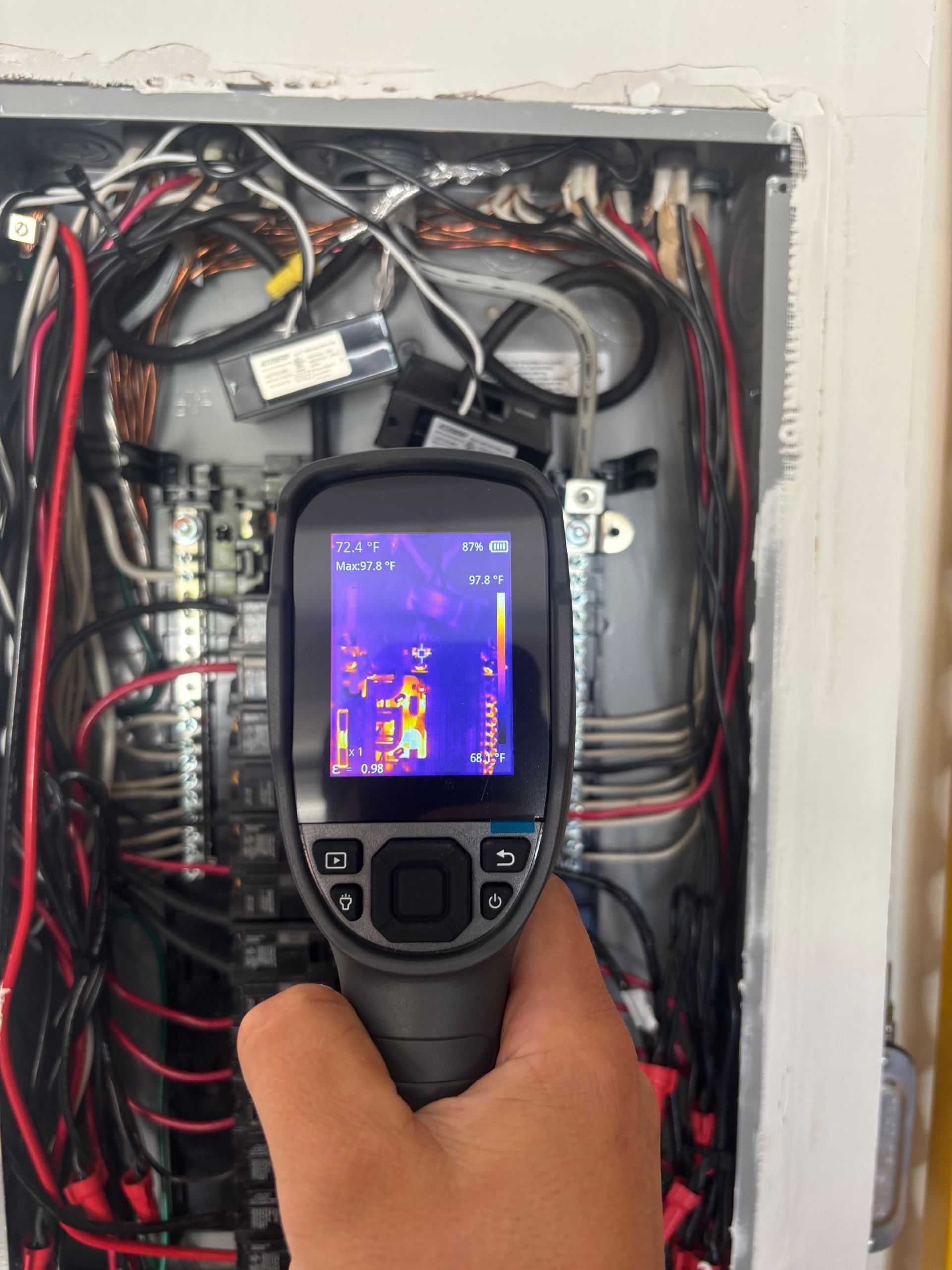 Handheld thermal camera scanning exposed electrical wiring in a wall panel
