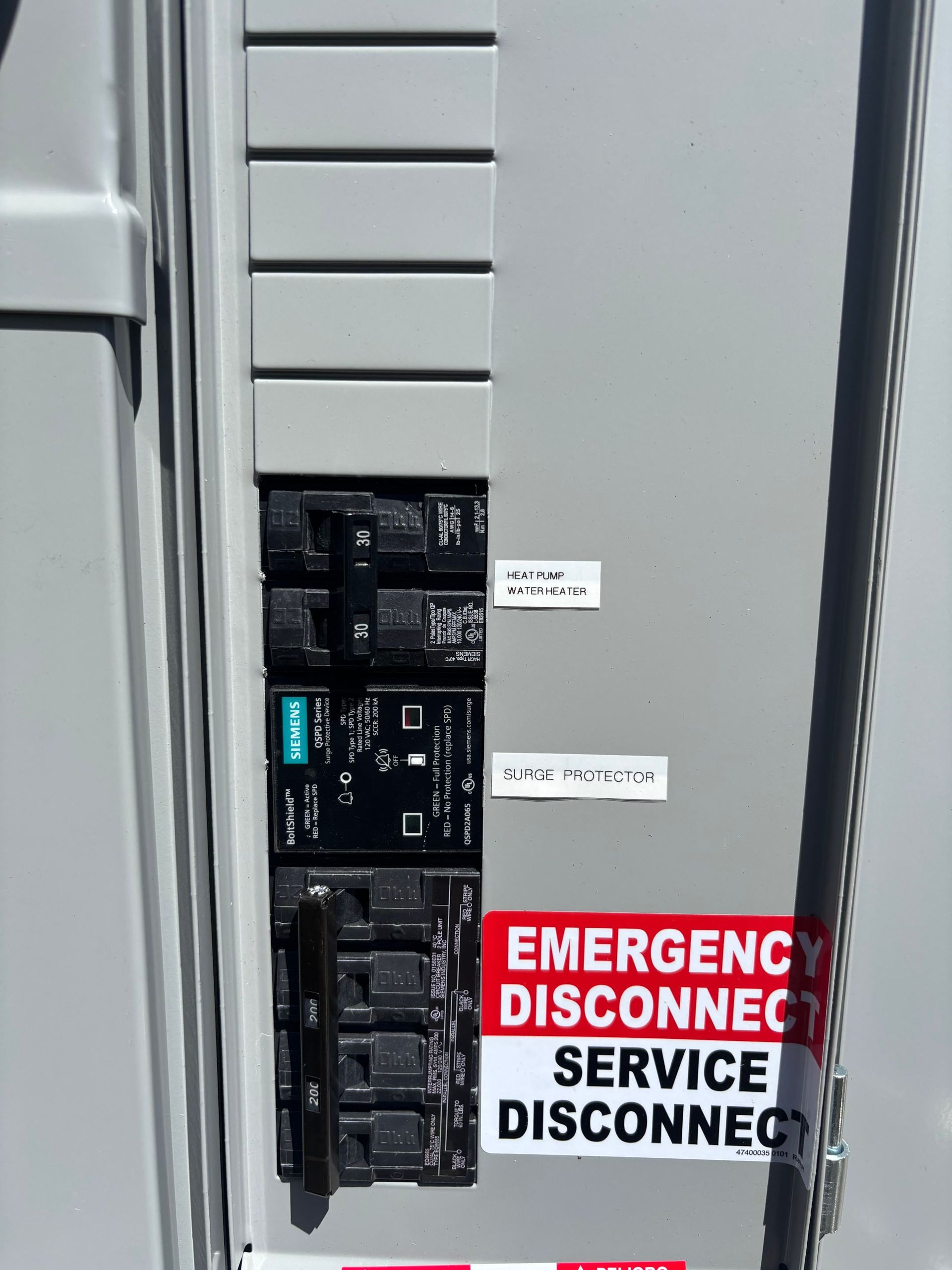 Electrical service disconnect panel with red “EMERGENCY DISCONNECT” label and circuit breakers.