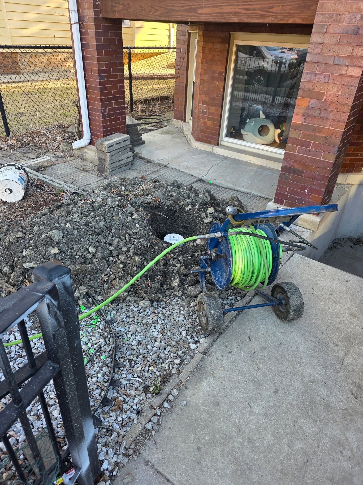 Blue pipe being installed in an underground trench with a hose and equipment nearby