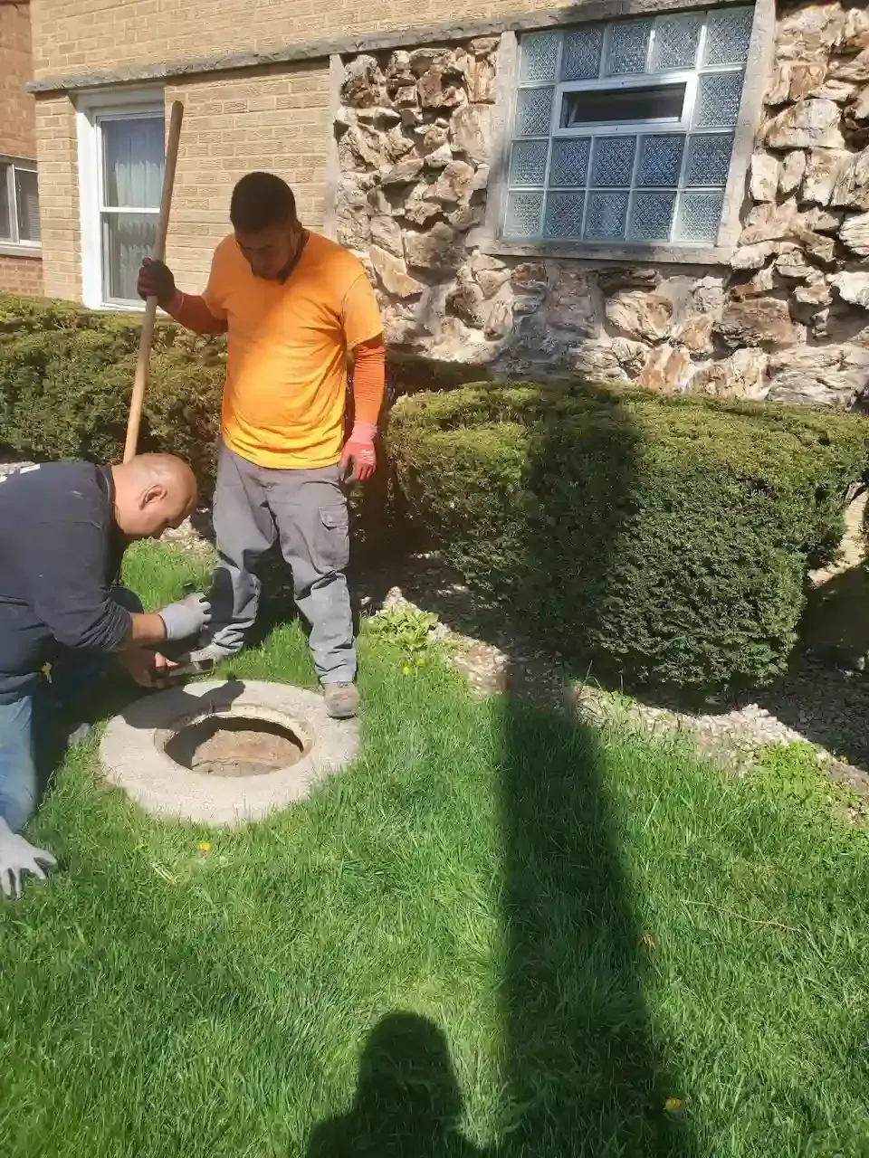 Hands adjusting a white water heater control panel with a screwdriver and hose in a bathroom