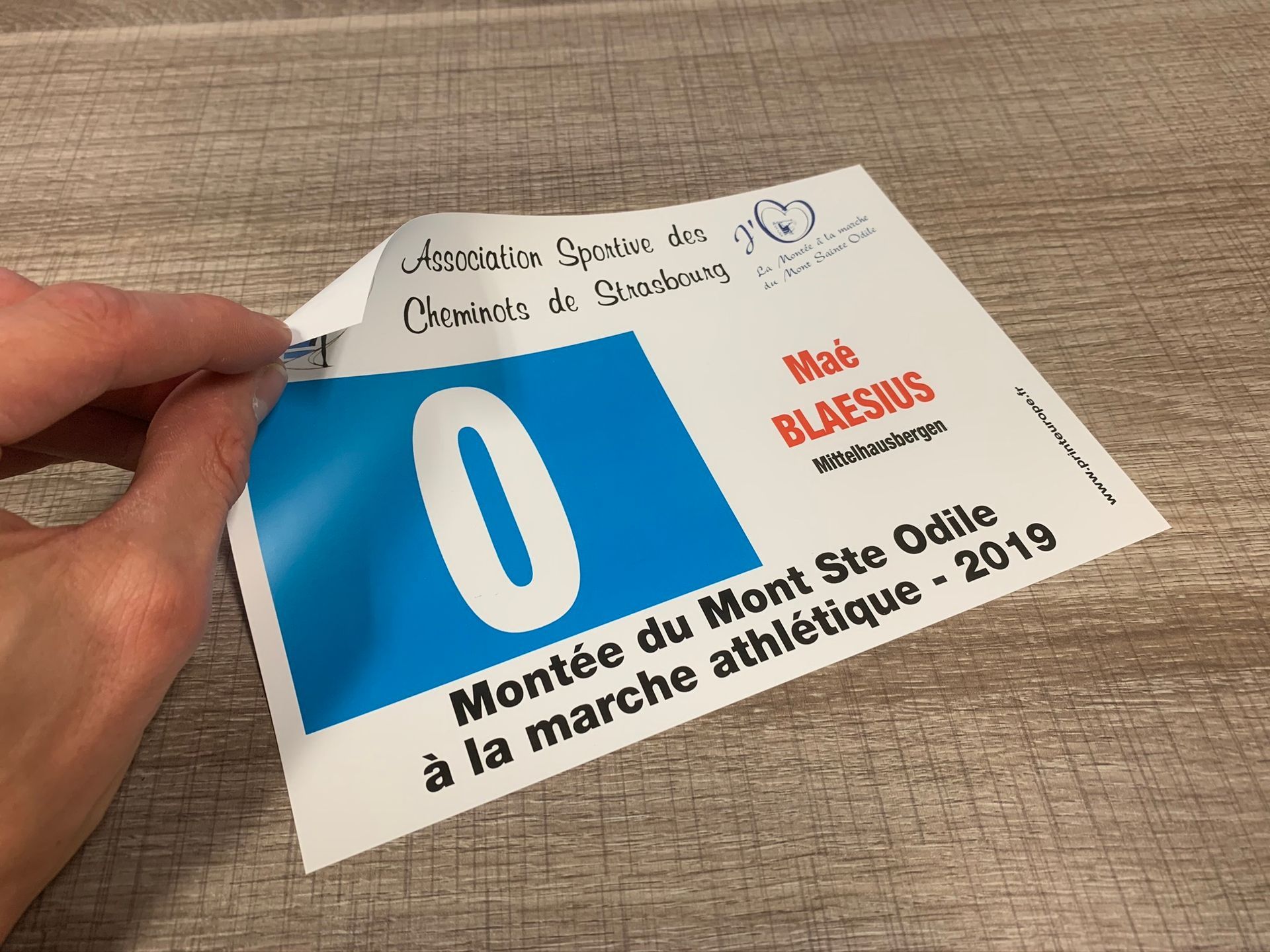 Une personne tient un morceau de papier avec le numéro 0 dessus.