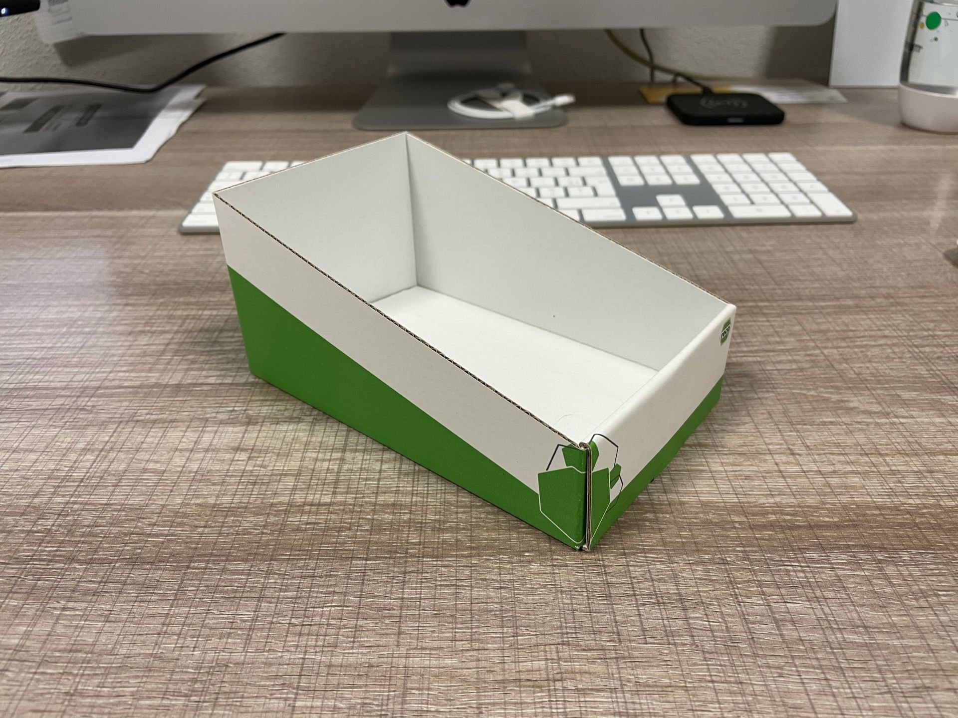 Une boîte blanche et verte est posée sur un bureau devant un écran d'ordinateur.