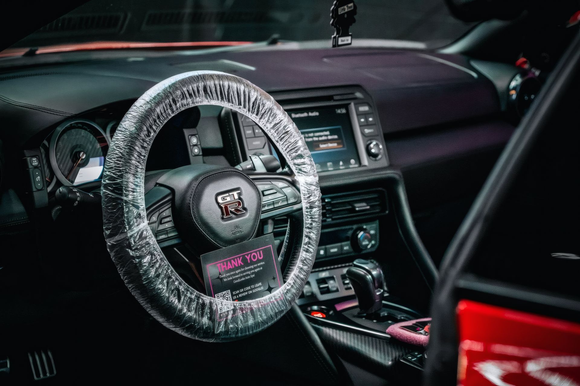 Car interior with a clear protective steering wheel cover and red accents on the center console