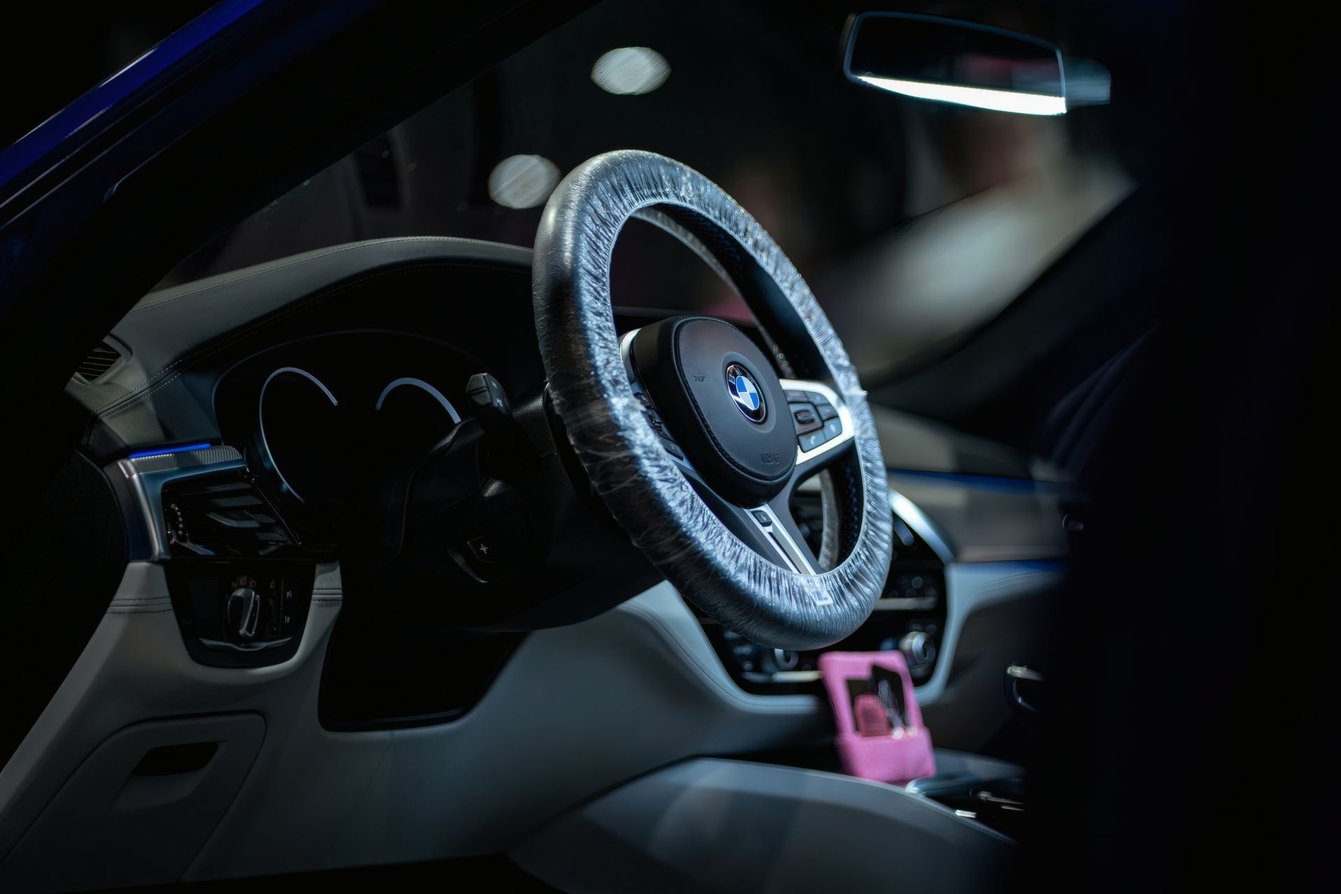Luxury car interior with illuminated steering wheel and pink item