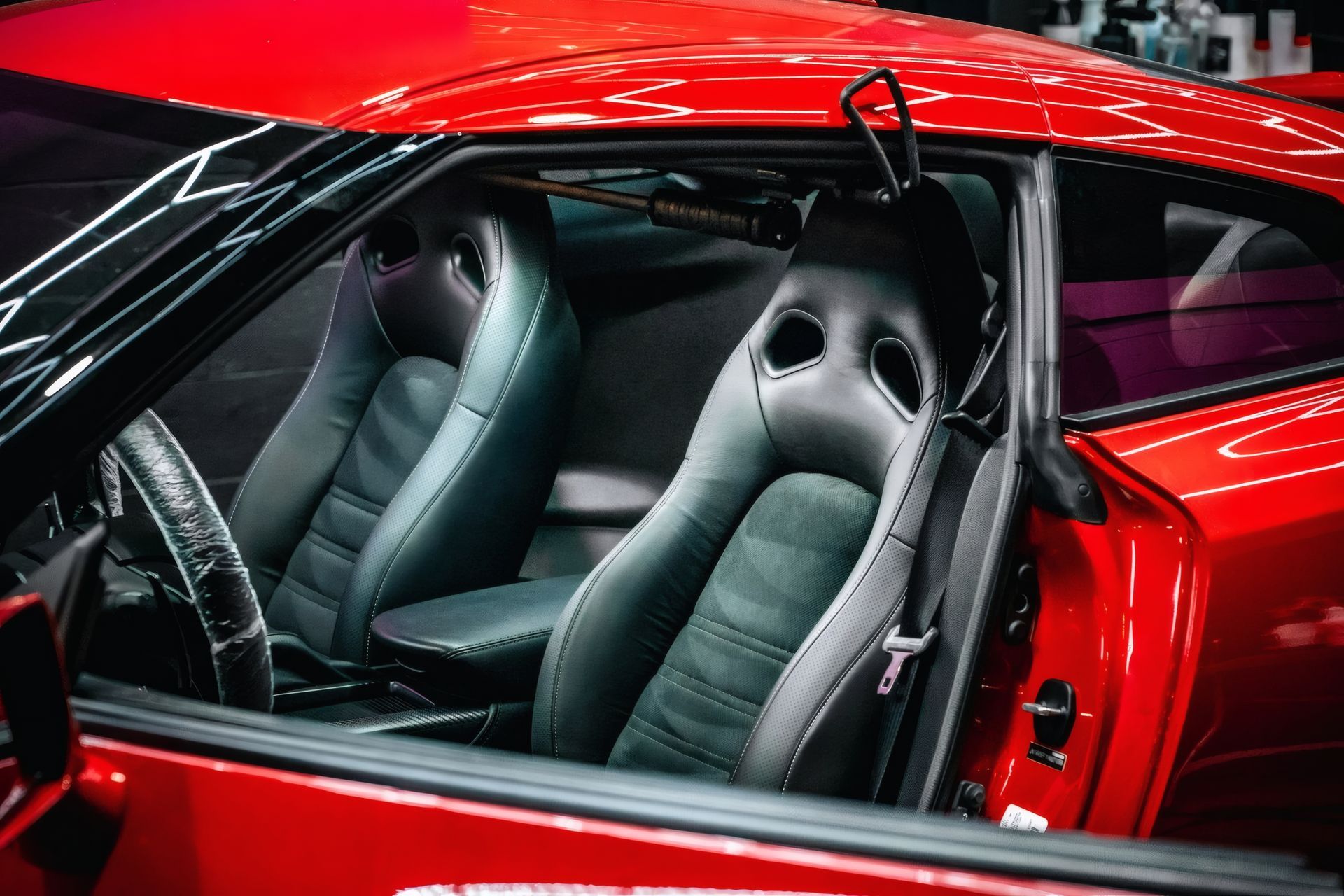 Red sports car interior with black racing seats and a visible steering wheel through the open side window