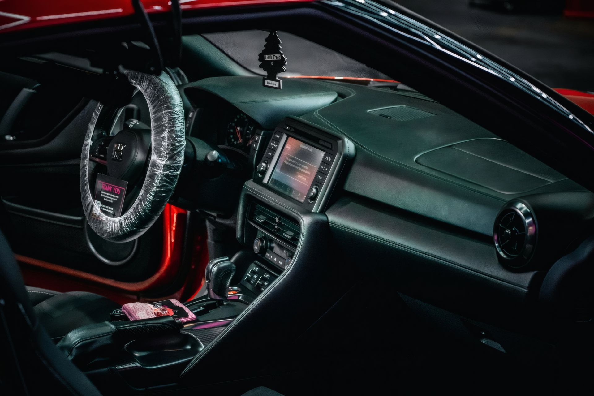 Customized black car interior with red ambient lighting and a patterned steering wheel