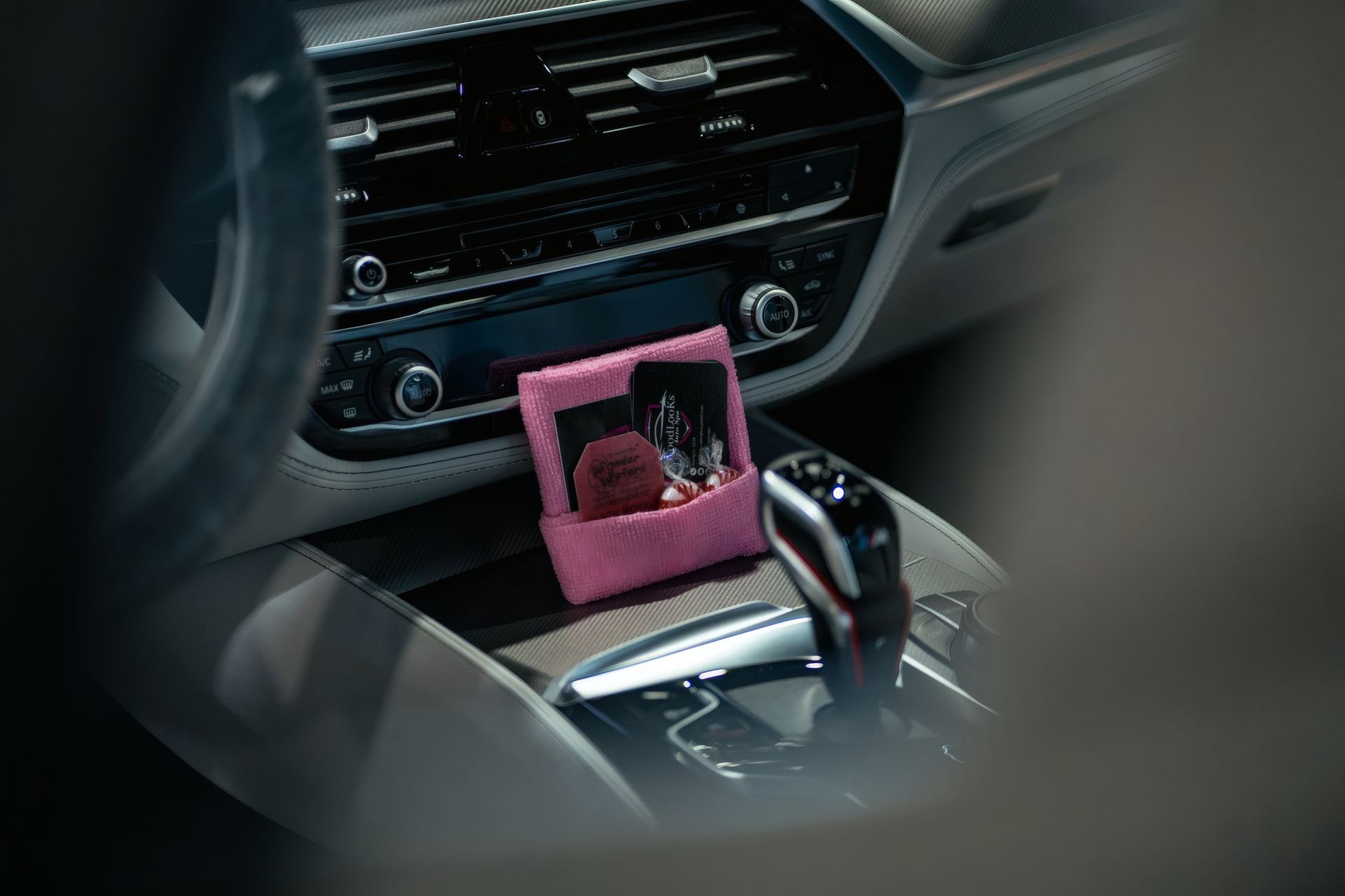 Car dashboard with a pink item on the center console and gear shift visible.