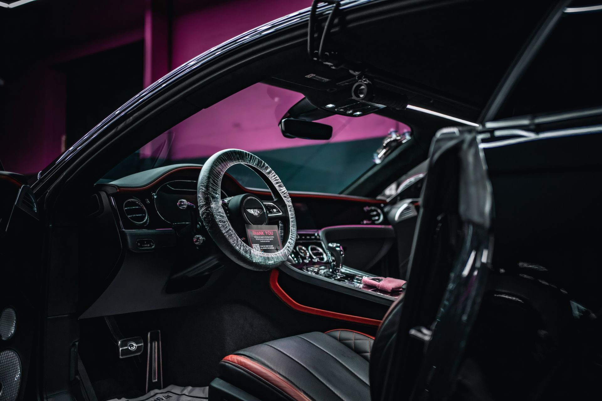 Luxury car interior with black and orange accents and a custom steering wheel