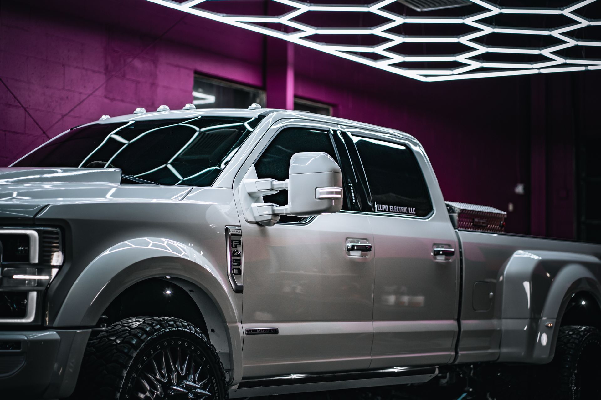 Silver pickup truck in a showroom with purple walls and geometric neon ceiling lights