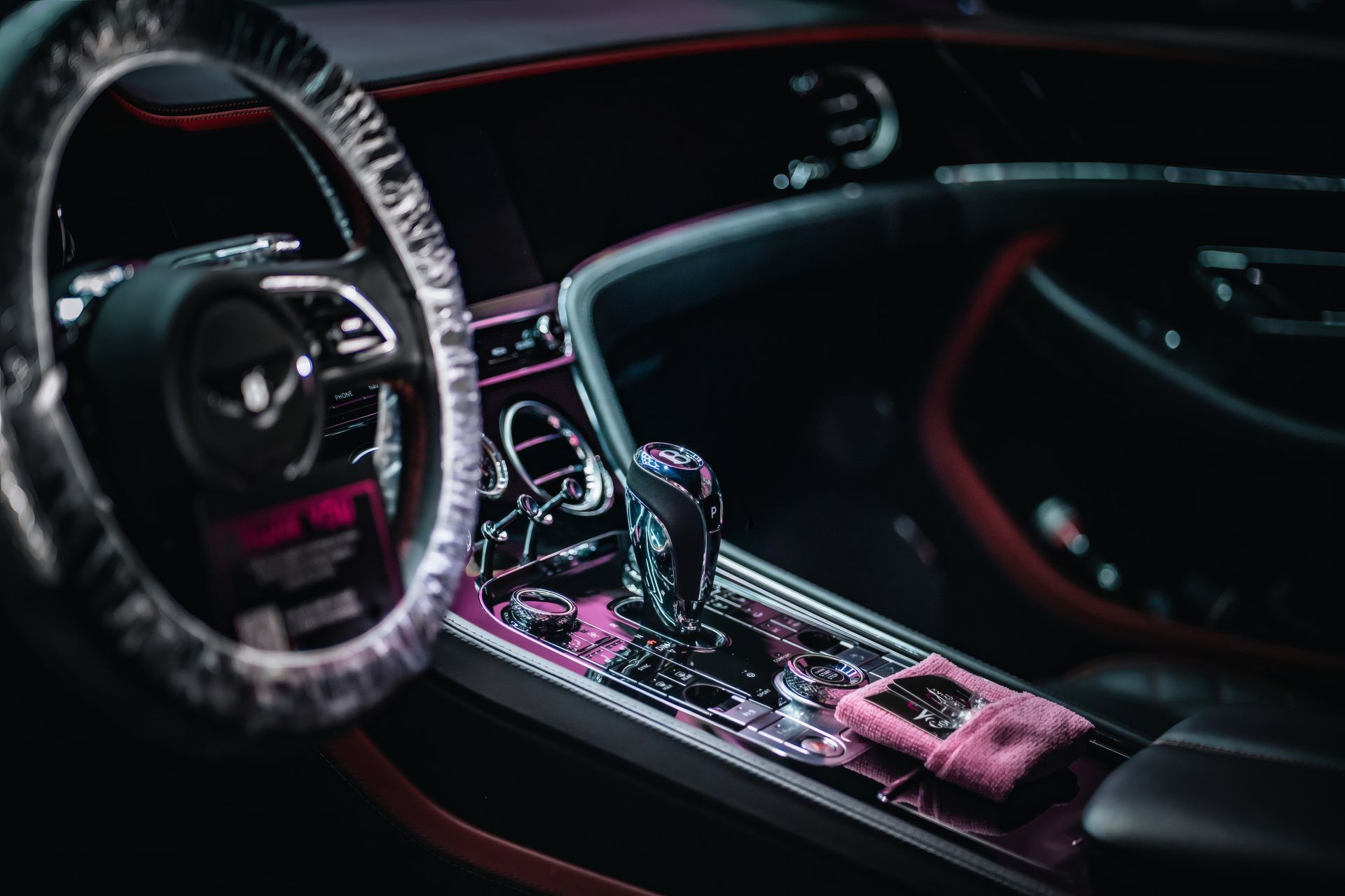 Luxury car interior with orange-accented dashboard, steering wheel cover, and gear shift