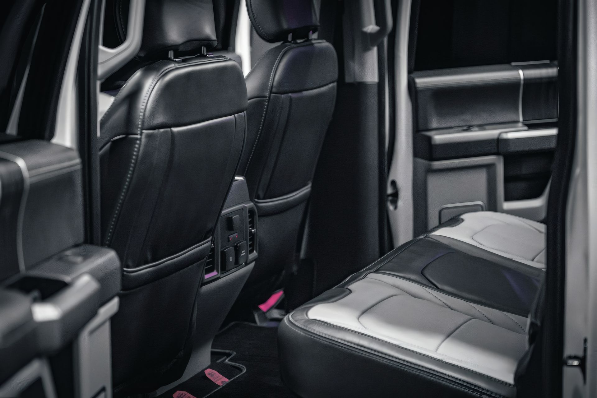 Rear interior of a black vehicle with leather seats and a folded center armrest