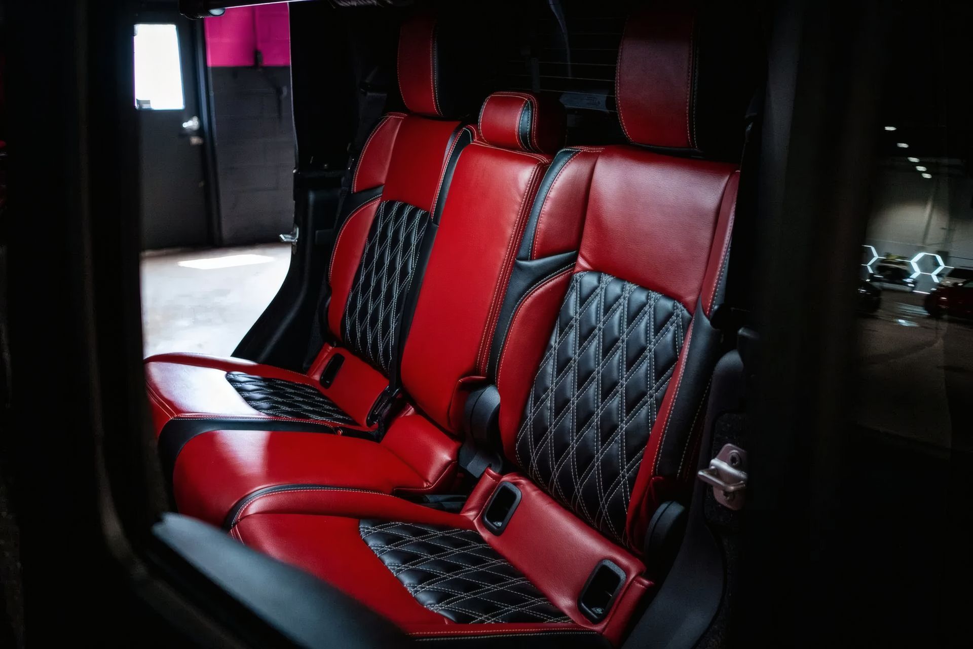 Red and black leather van seats with diamond stitching inside a dark vehicle interior