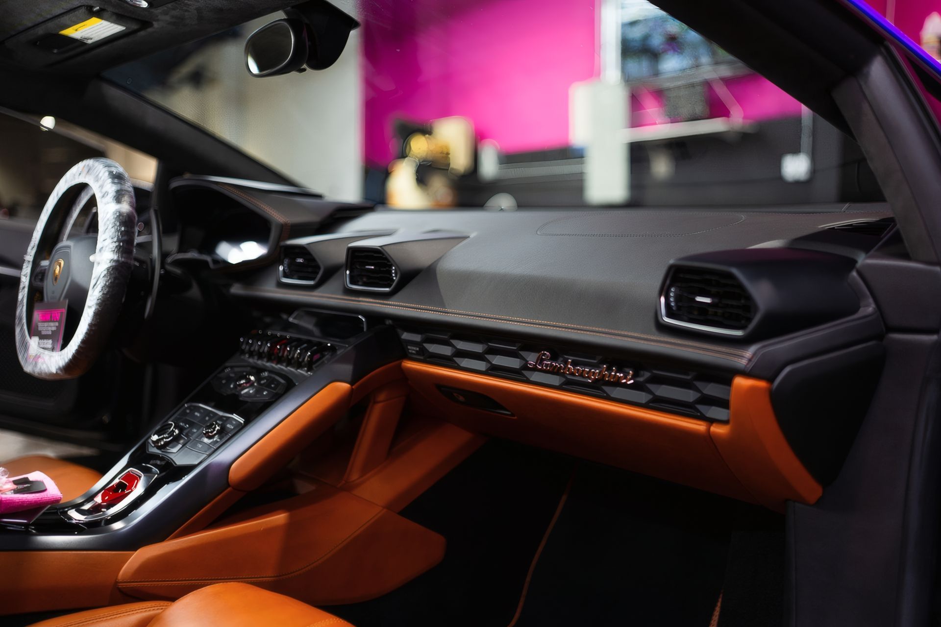 Luxury sports car interior with black and orange dashboard, steering wheel, and center console